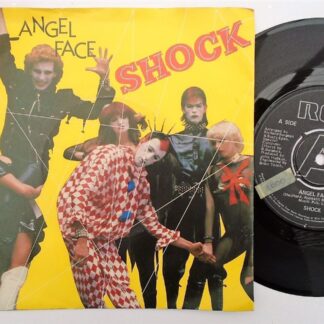 Shock Angel Face 7" RCA RCA14 VG/VG 1980 picture sleeve. There is a pressing fault on side one. A small piece of debris is pressed under the track. It doesn't skip but is very slightly audible for 20 seconds or so. It is only just worth mentioning. There is 2mm drill hole in label rim
